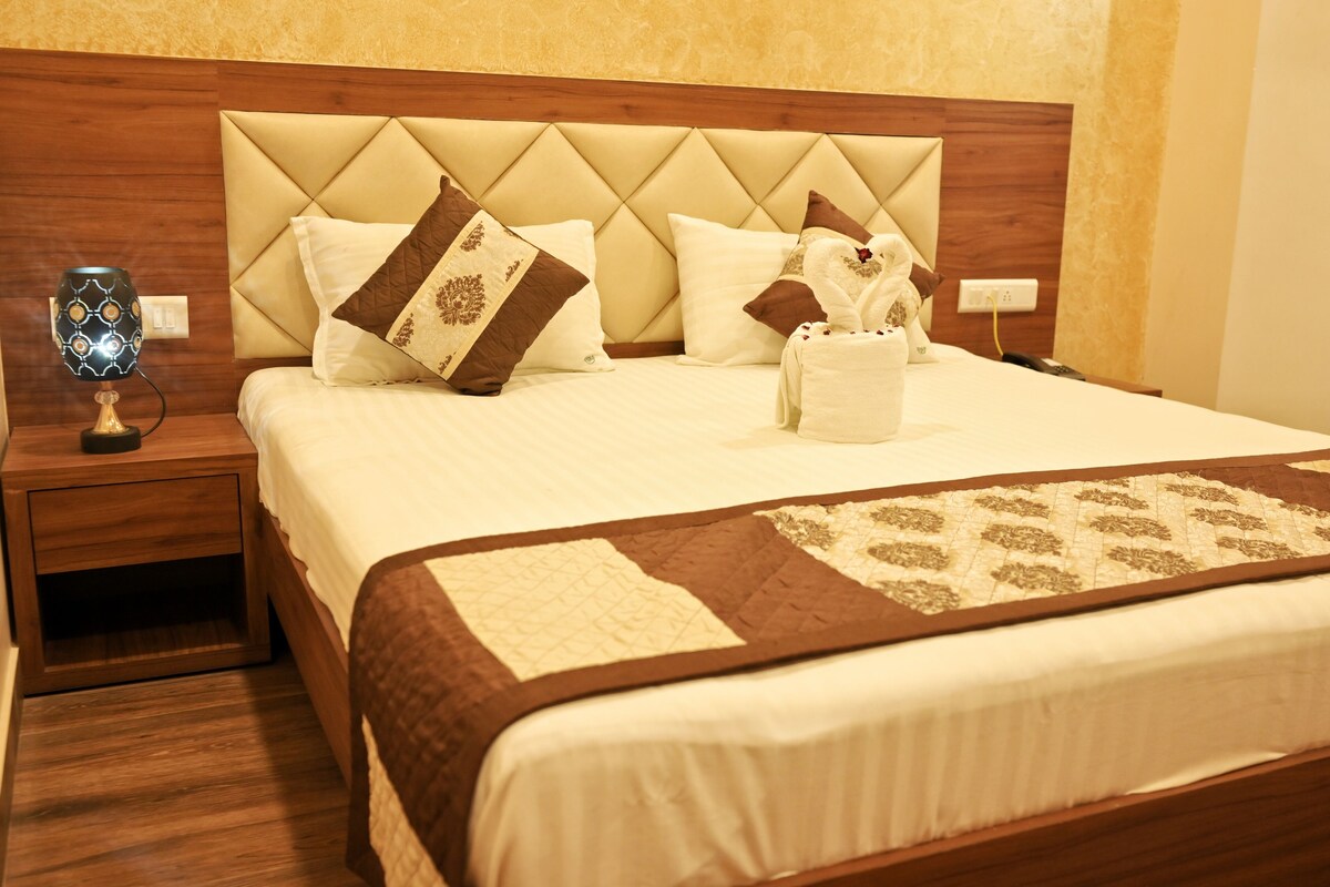 A neatly made bed with a quilted headboard, a bedside table with a lamp, and a decorative item on the bed.