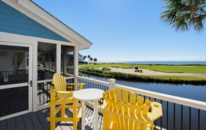A deck with yellow chairs and a table overlooking a golf course and water. - Golf & Ocean Views - Resort Access Included! (Fripp Island)