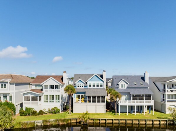 A row of waterfront homes with a grassy lawn and a dock.