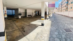A covered outdoor area with hexagonal tiles, a fire extinguisher, a bench, and a potted plant. - Tropical Beach / Center - Cabo Frio (Cabo Frio)