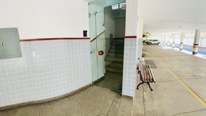 A clean, tiled corridor with a bench and a staircase leading to a parking area. - Tropical Beach / Center - Cabo Frio (Cabo Frio)