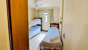 A room with a bunk bed, a single bed, a ceiling fan, and a window with curtains. - Tropical Beach / Center - Cabo Frio (Cabo Frio)