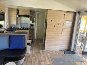 A compact kitchenette with a microwave, sink, and stove, a seating area with a sofa and cushions, and a dining table with chairs.