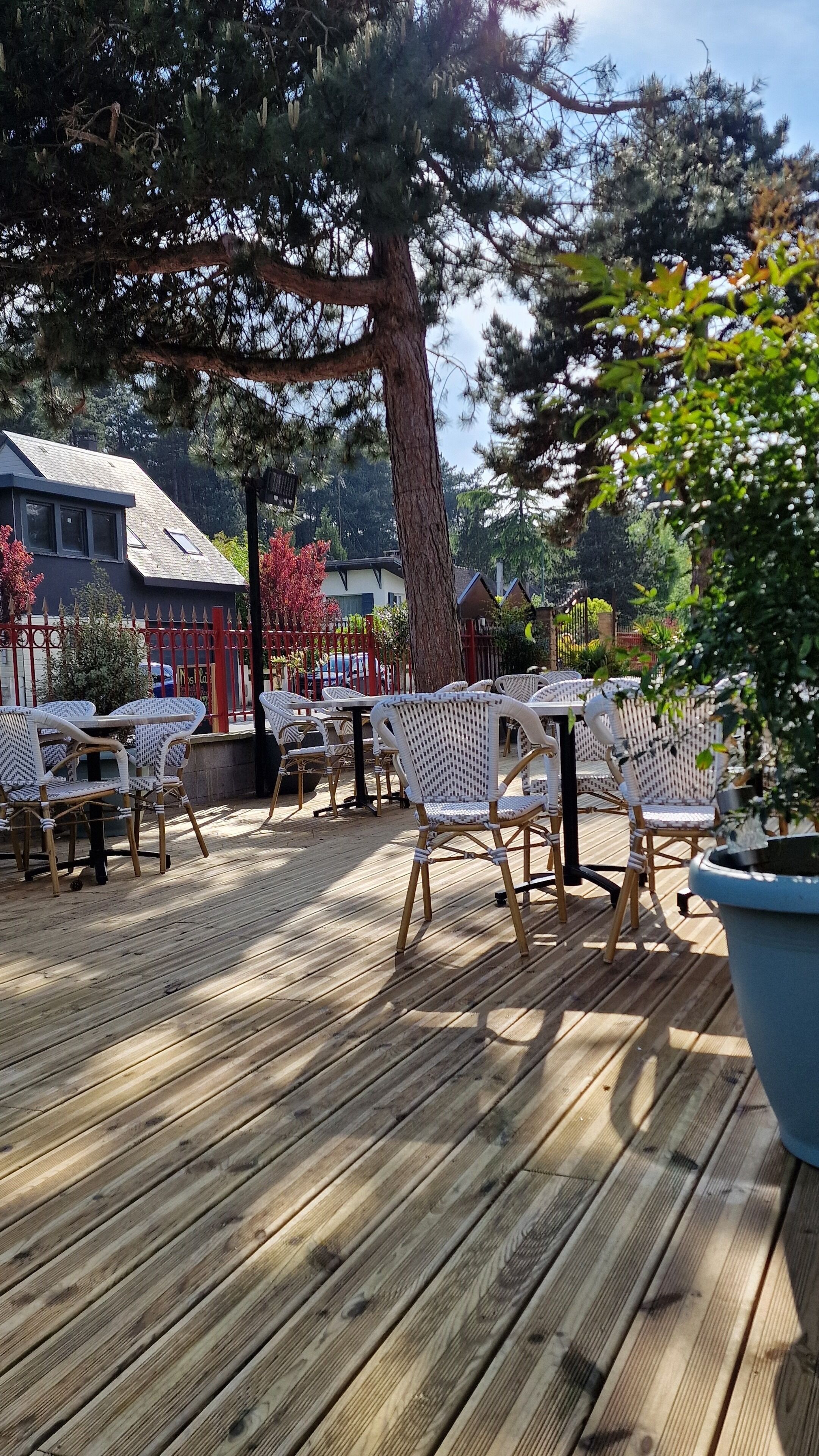 An outdoor patio with wooden flooring, wicker chairs, and tables.
