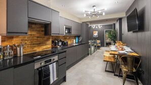 A modern kitchen with dark cabinetry, a stainless steel microwave, and a wooden dining table with chairs.