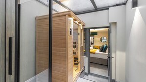 A modern hotel room with a wooden wardrobe, a bed with yellow bedding, and a mirror on the wall.