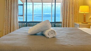Una camera d'albergo con un letto, vista sul mare e una lampada sul comodino.