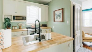A kitchen with white cabinets, a microwave, a sink, and a stove. - The Garden House (Lancaster)