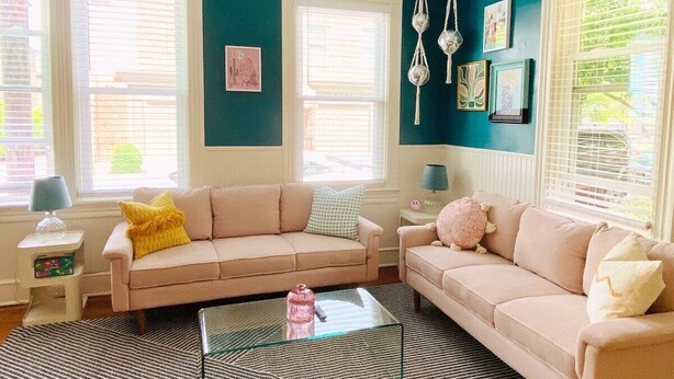 A living room with two sofas, a glass coffee table, and a wall decorated with framed pictures. - The Garden House (Lancaster)