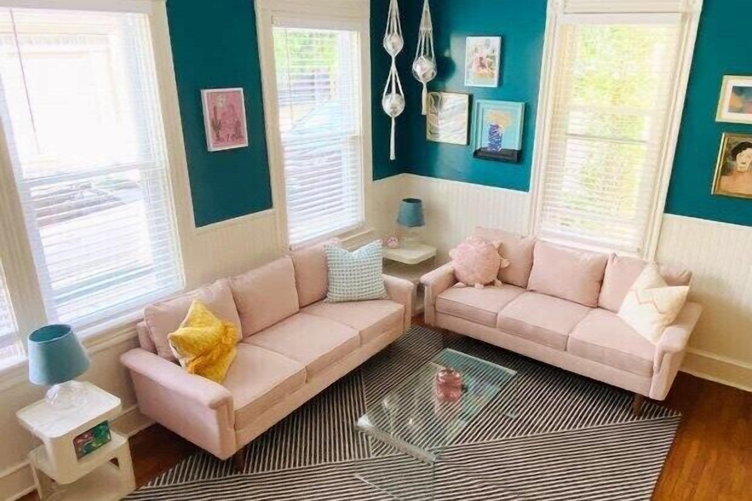 Una sala de estar con dos sofás rosas, una mesa de centro de vidrio y un tapete a rayas.