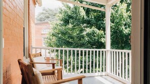 A covered balcony with wooden furniture and a white railing. - The Garden House (Lancaster)