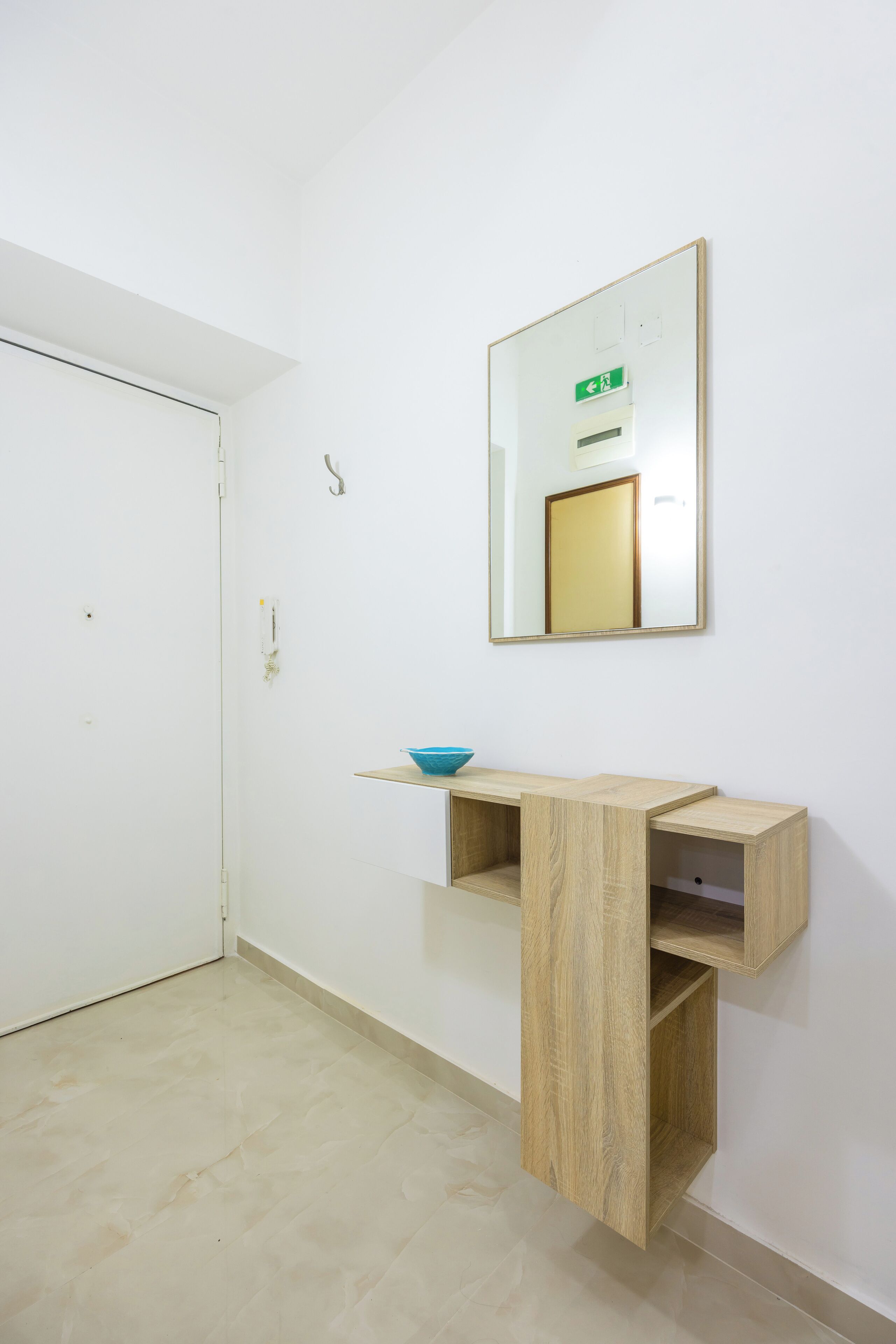 A room with a wooden console table, a blue bowl, and a mirror on the wall.