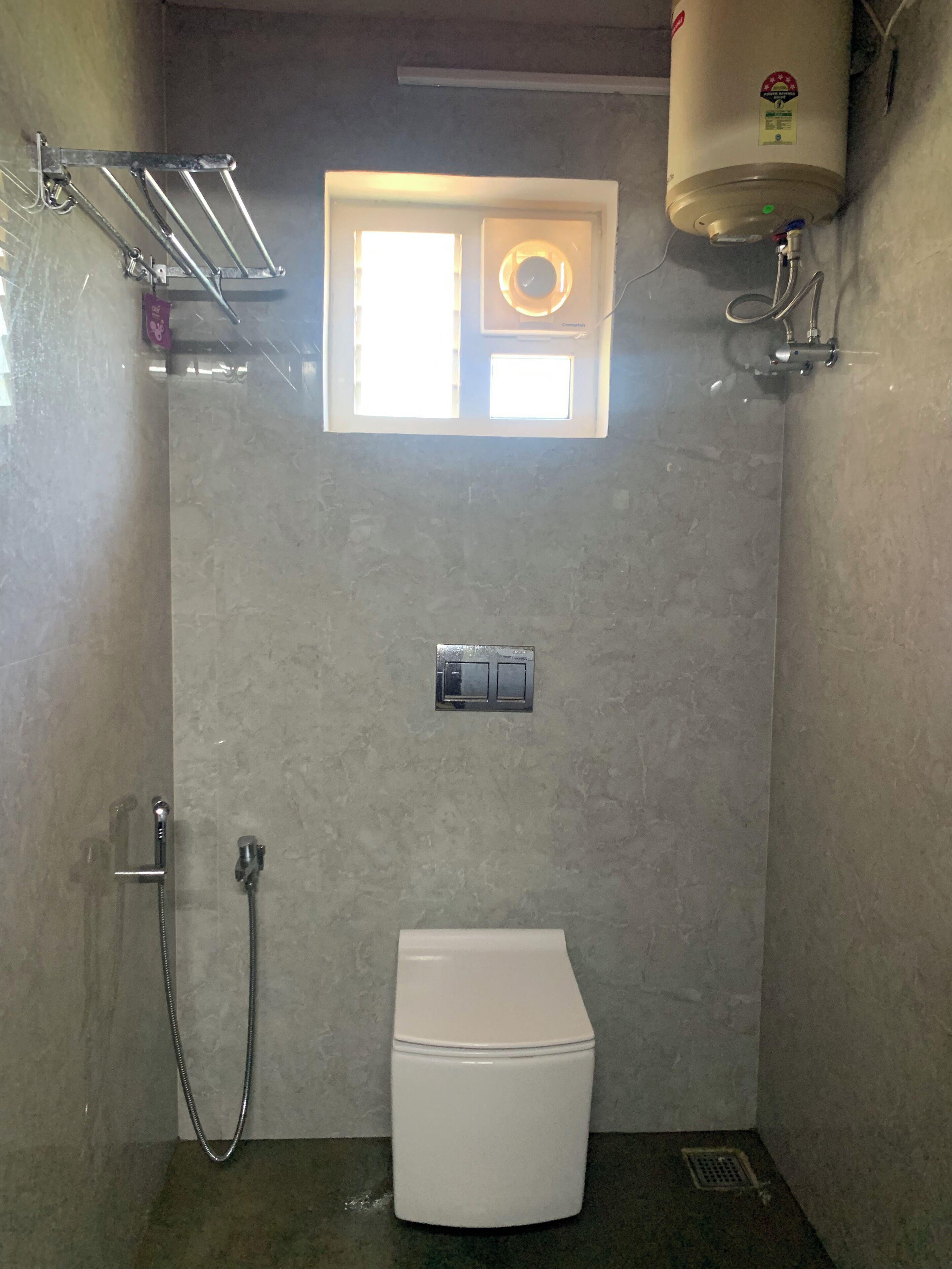 Ein kleines, kompaktes Badezimmer mit Toilette, Dusche und Fenster.