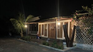Une maison avec un porche, une porte en bois et un petit jardin.