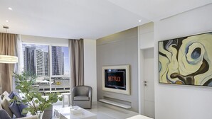 En moderne stue med et stort vindue, et Netflix-skilt, en grå lænestol og et moderne maleri.