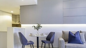 Et moderne værelse med et rundt bord, to stole, en sofa med puder og en vase med en plante.