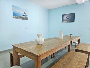 A dining area with a wooden table, benches, and a vase. There are two paintings on the walls. - Zen-inspire Villa in Jaco (Jaco)