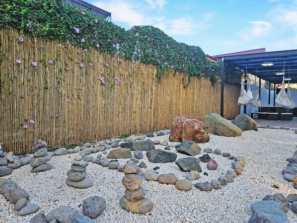 A garden with a bamboo fence, rocks, and a large boulder.