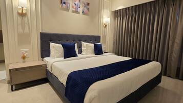 Une chambre d’hôtel moderne avec un grand lit, une table de chevet, un climatiseur fixé au mur et une fenêtre avec des rideaux.