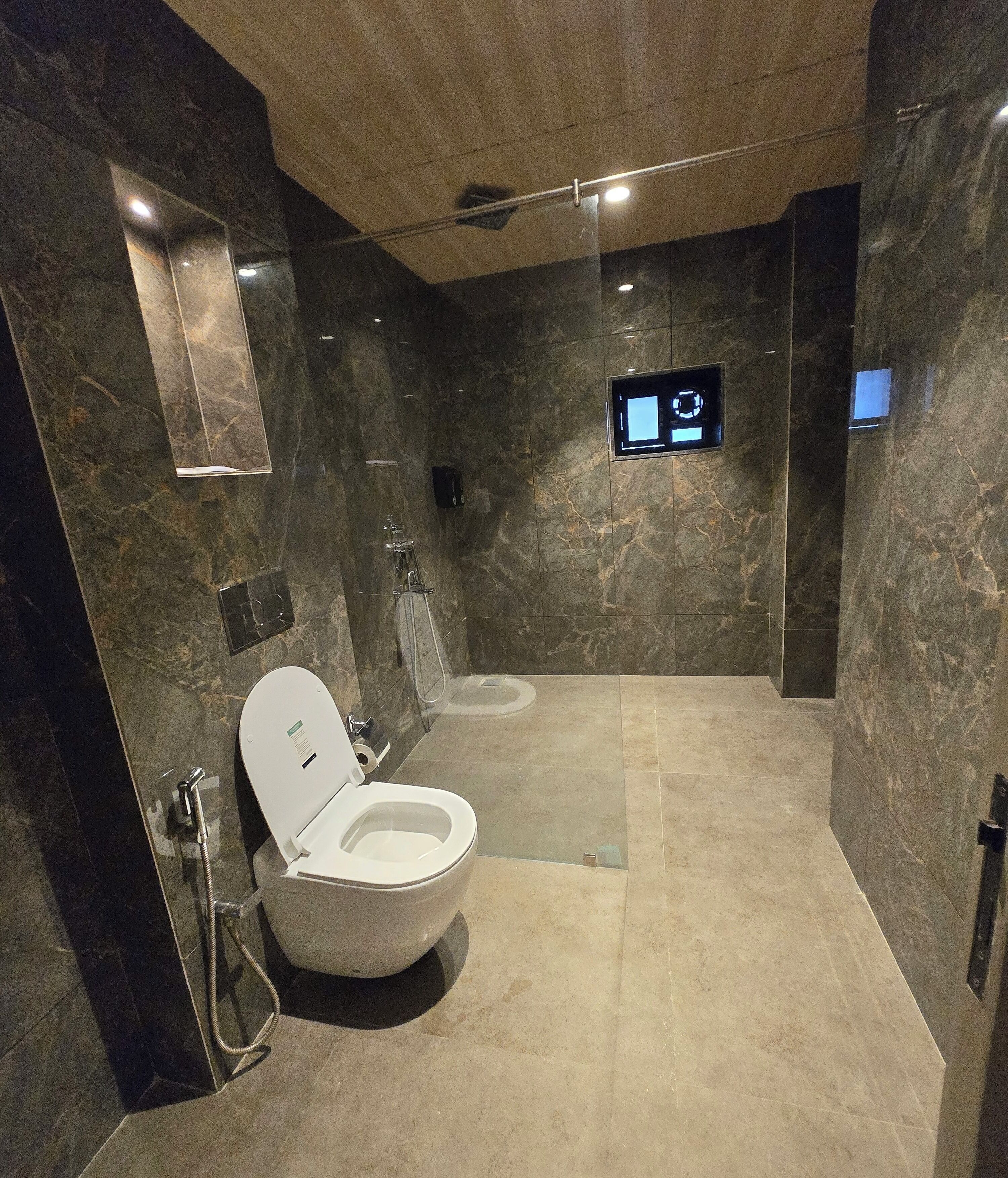 A modern bathroom with a toilet, shower, and a digital control panel on the wall.