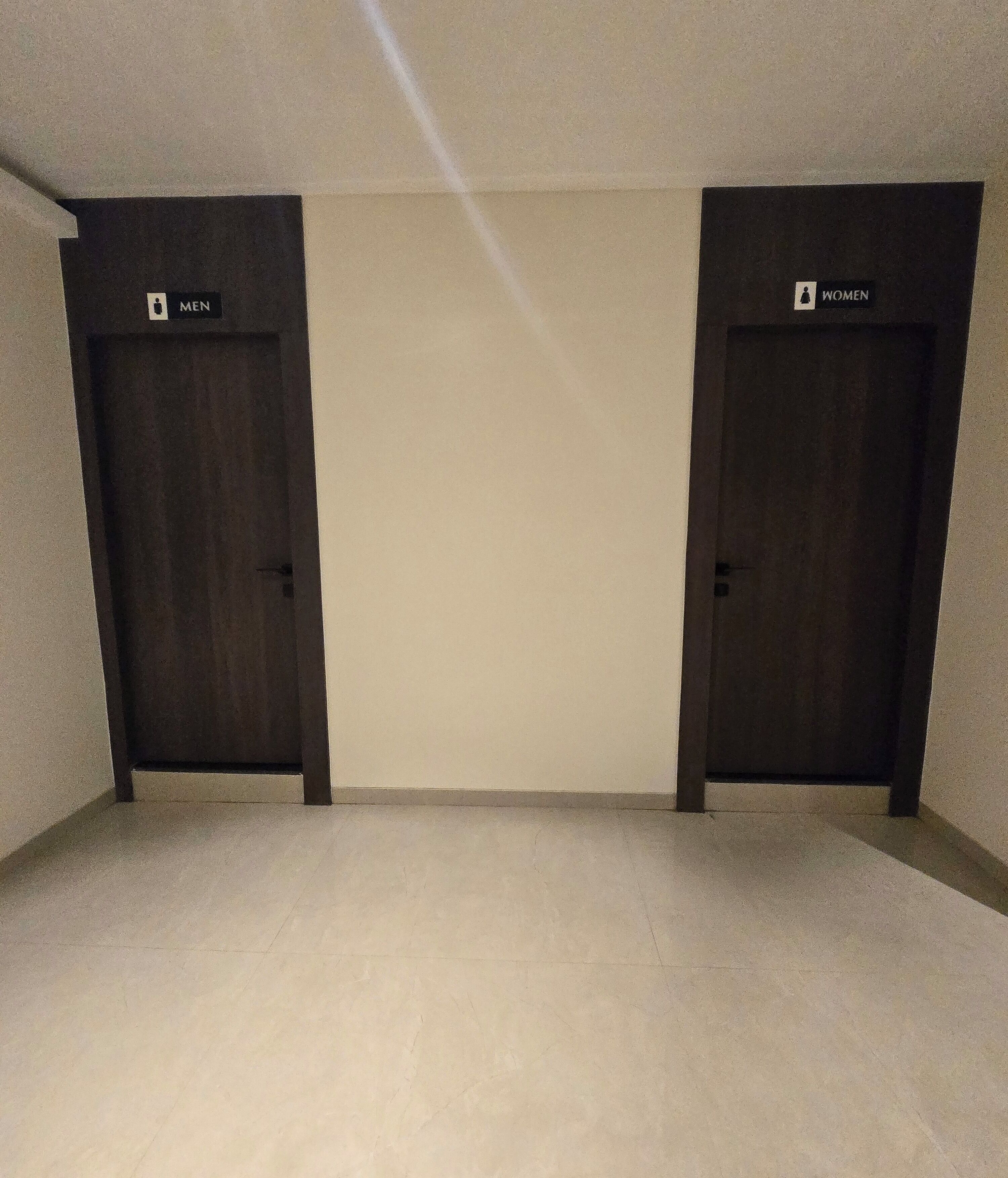 Two doors labeled "MEN" and "WOMEN" in a hallway with a plain tiled floor.