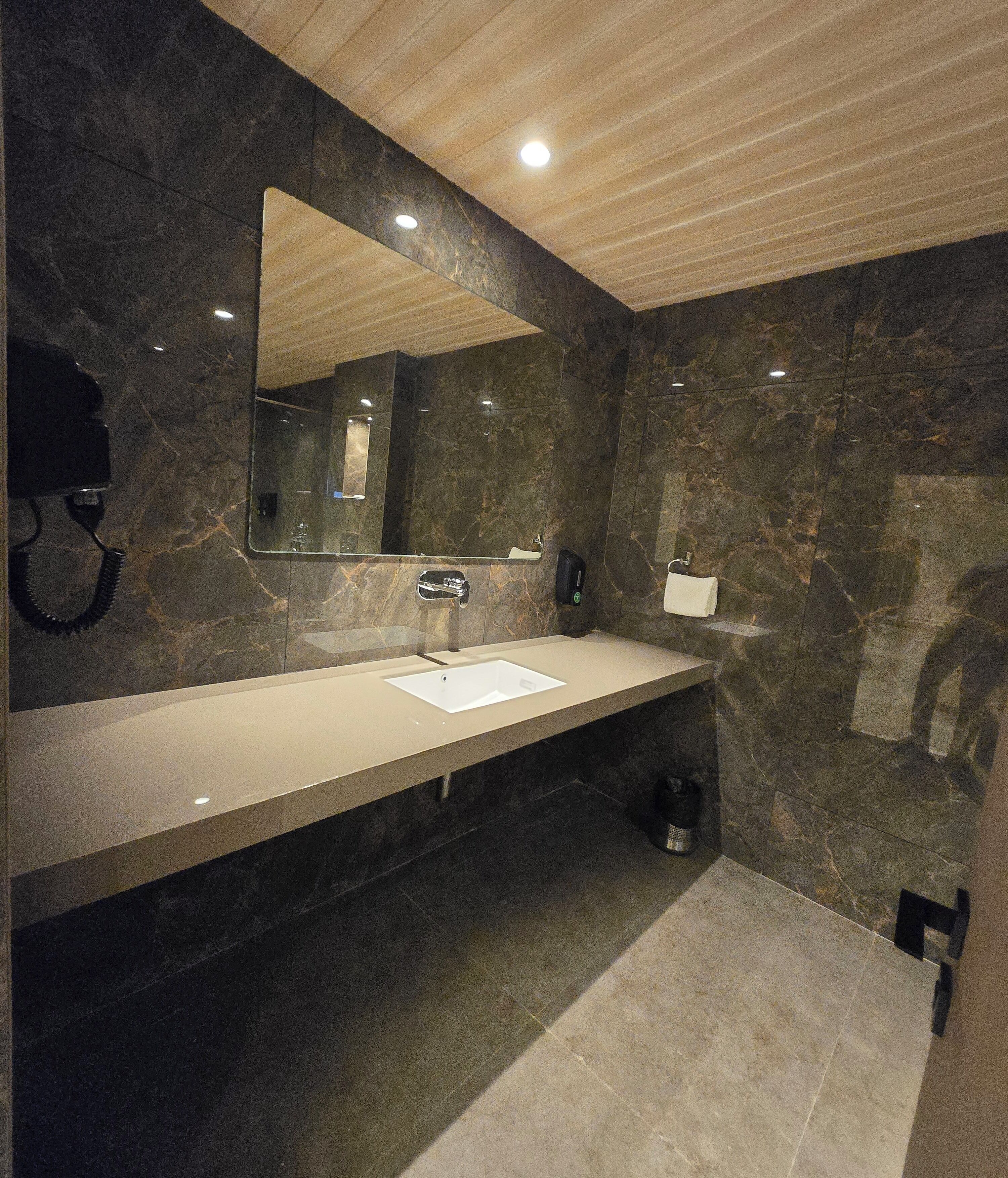 A modern bathroom with a marble vanity, a large mirror, and a shower area.