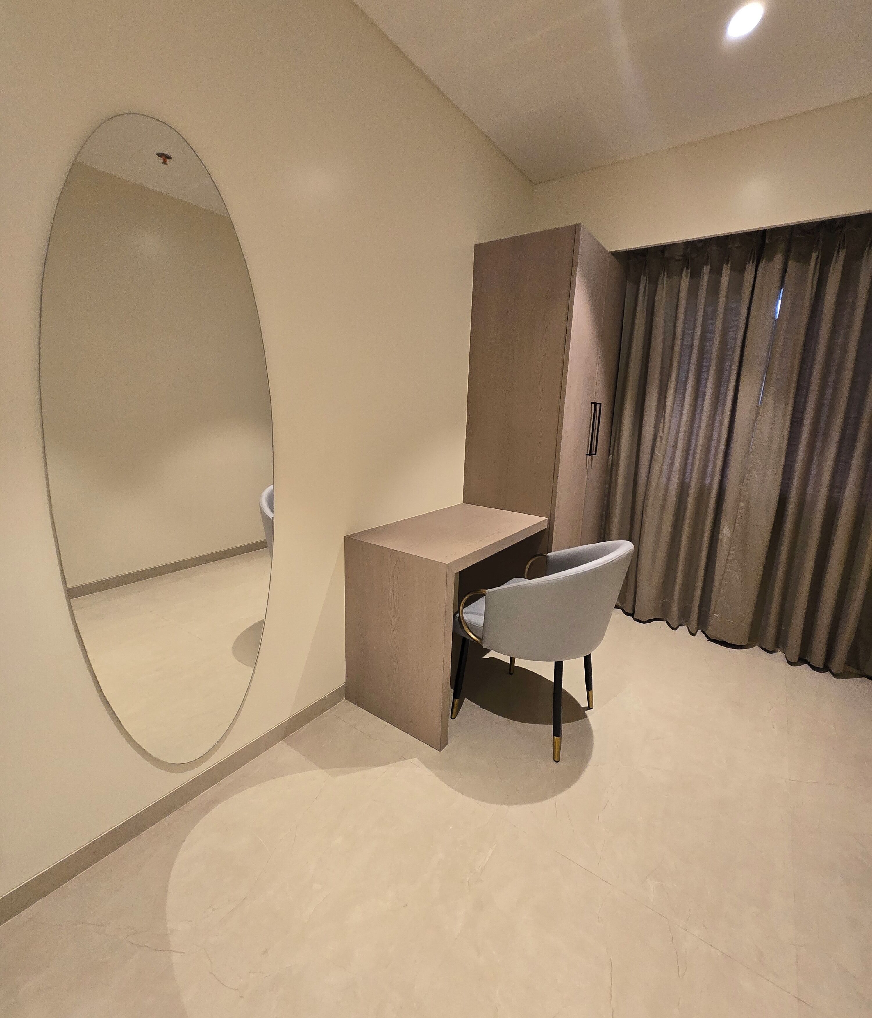 Een moderne kamer met een bureau, stoel en een grote spiegel.