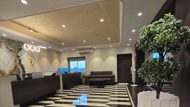 A modern lobby with a geometric patterned floor, a reception desk, a sofa, and a large potted plant. - Western Hotel (Chandrapur)
