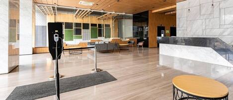 A modern lobby with a wooden ceiling, a reception desk, seating area, and a marble wall.