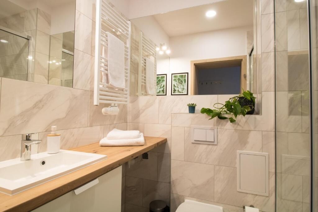 A modern bathroom with a marble vanity, a sink, a mirror, and a shower area.
