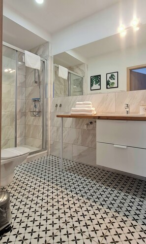 Un baño moderno con ducha, inodoro y lavamanos.