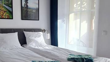 Een moderne slaapkamer met een groot bed, een nachtkastje, een wandlamp en twee ingelijste foto's.