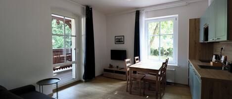 A compact living space with a dining area, a small kitchen, and a seating area by the window.