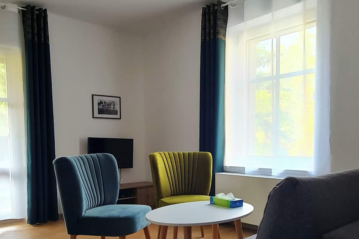 Una sala de estar moderna con un sofá, dos sillones, una mesita y un ventilador de techo.