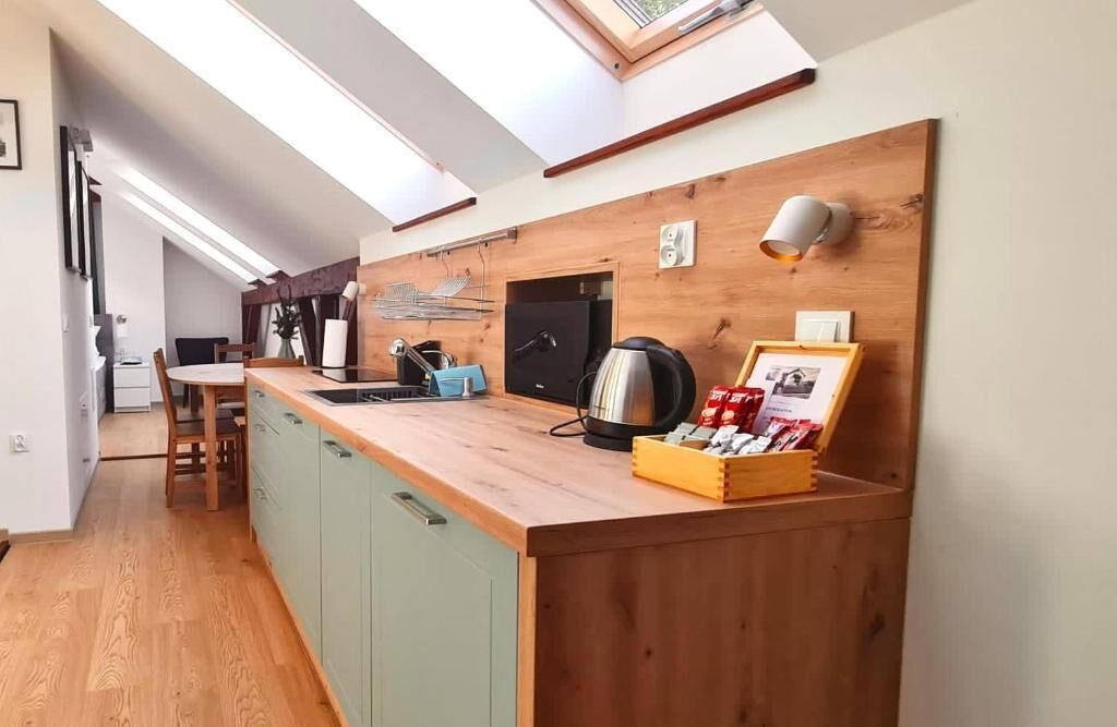 Una cocina compacta con encimera de madera, hervidor, cafetera y un cuadro enmarcado.