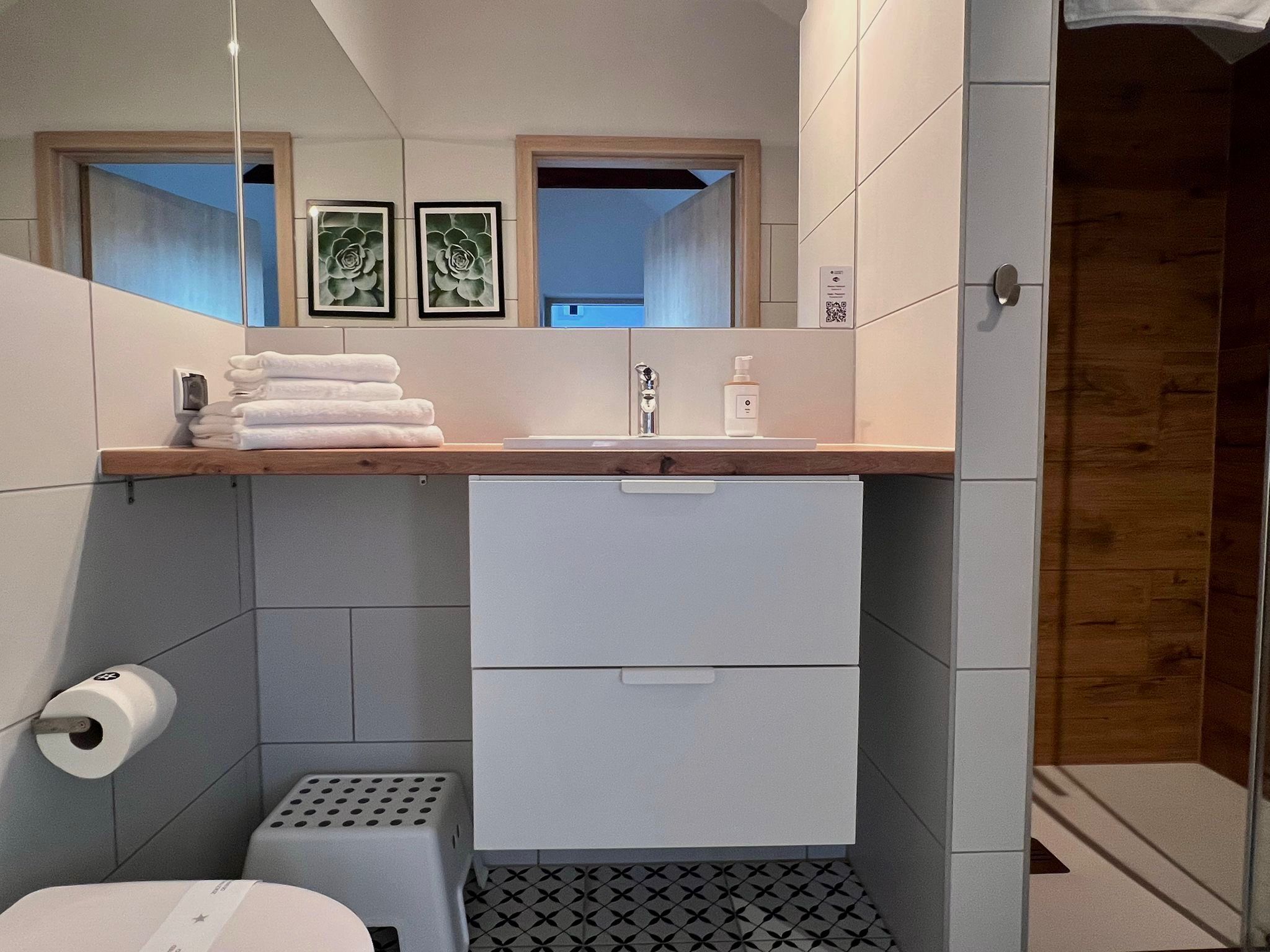 Un baño moderno con inodoro, lavamanos y un pequeño cubo de basura.