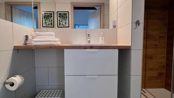 Un baño moderno con inodoro, lavamanos y un pequeño cubo de basura.