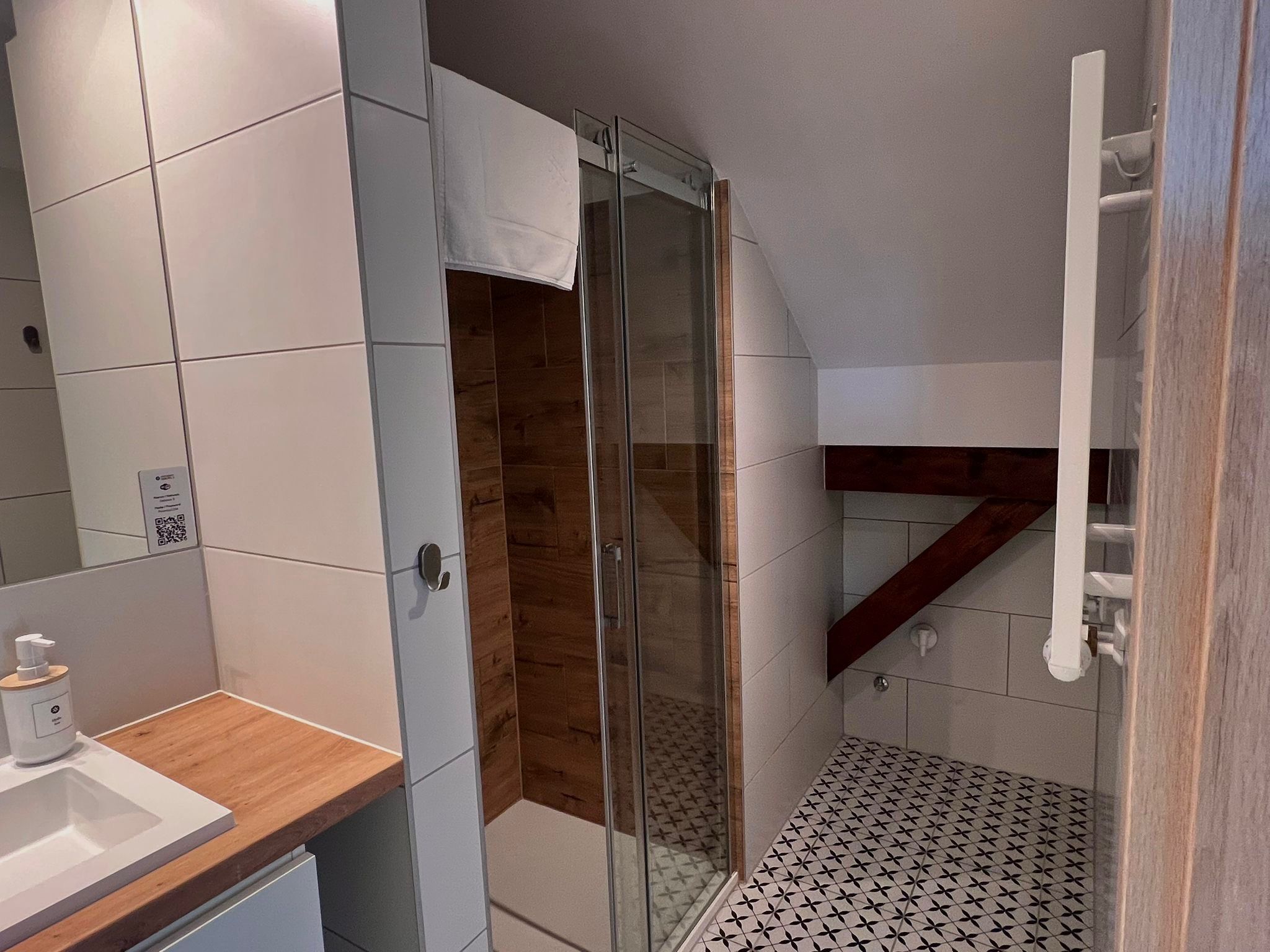 Un bagno moderno con box doccia in vetro, un mobile bagno in legno e un pavimento decorato.