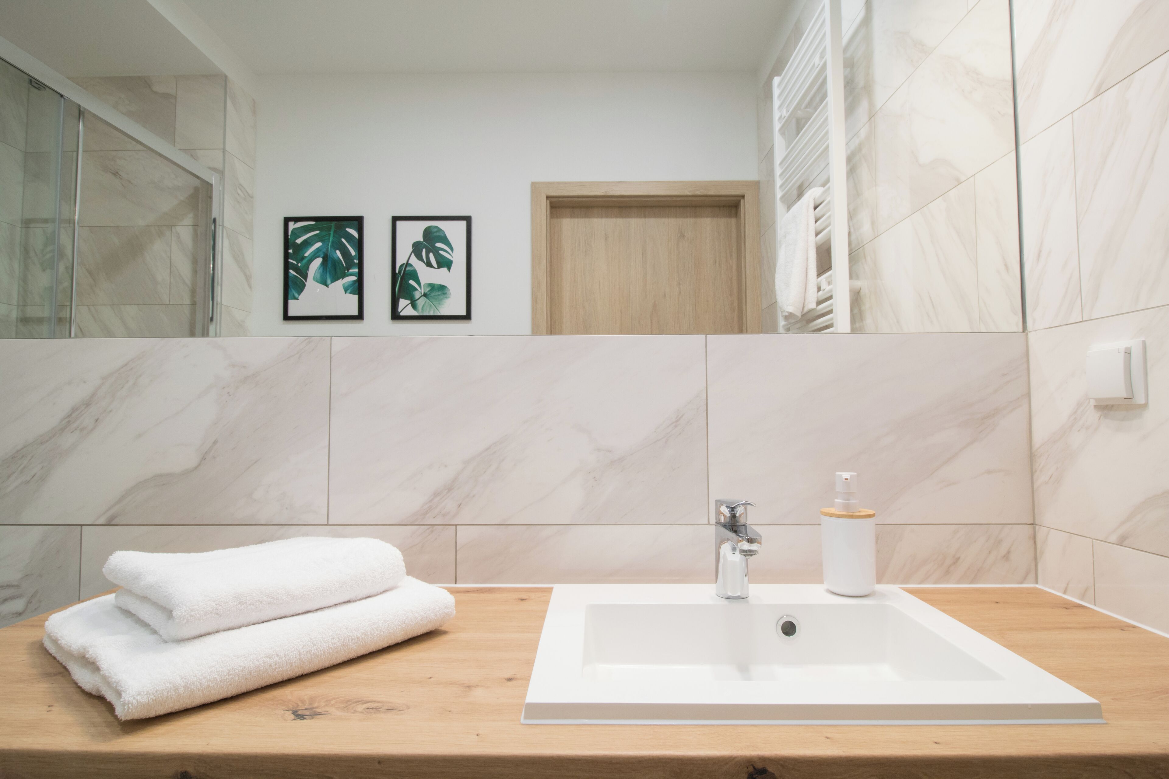 Un bagno con un lavandino bianco, un piano in legno e due quadri appesi al muro.