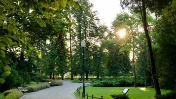 A paved pathway in a park with benches and a signpost.