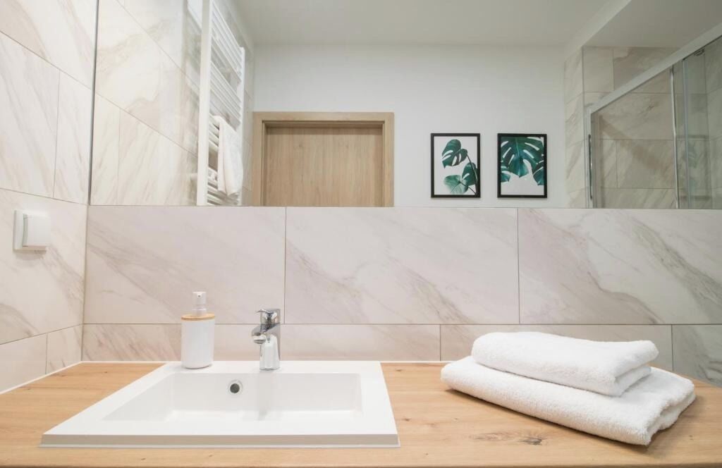 A bathroom with a large white bathtub, a wooden vanity, and two framed pictures on the wall.
