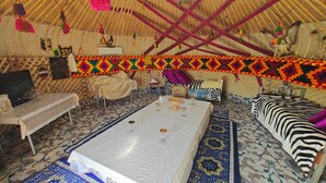 Una tienda tradicional con un tapete estampado, una mesa central con mantel blanco y un sofá con estampado de cebra.