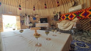 Comedor con mesa dispuesta para cuatro personas, con servicio de buffet y copas de vino.