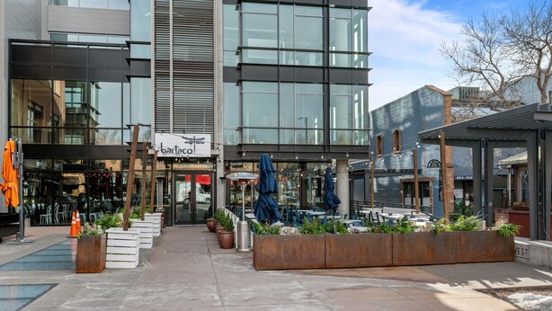 A modern building with a glass facade, outdoor seating area with umbrellas, and potted plants. - New Listing! Executive Rental - Steps to Vibrant Pearl Street Mall (Boulder)