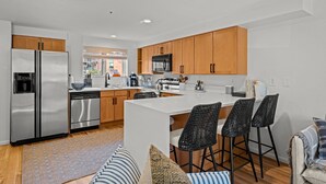 A modern kitchen with stainless steel appliances, wooden cabinets, and a central island with bar stools. - New Listing! Executive Rental - Steps to Vibrant Pearl Street Mall (Boulder)