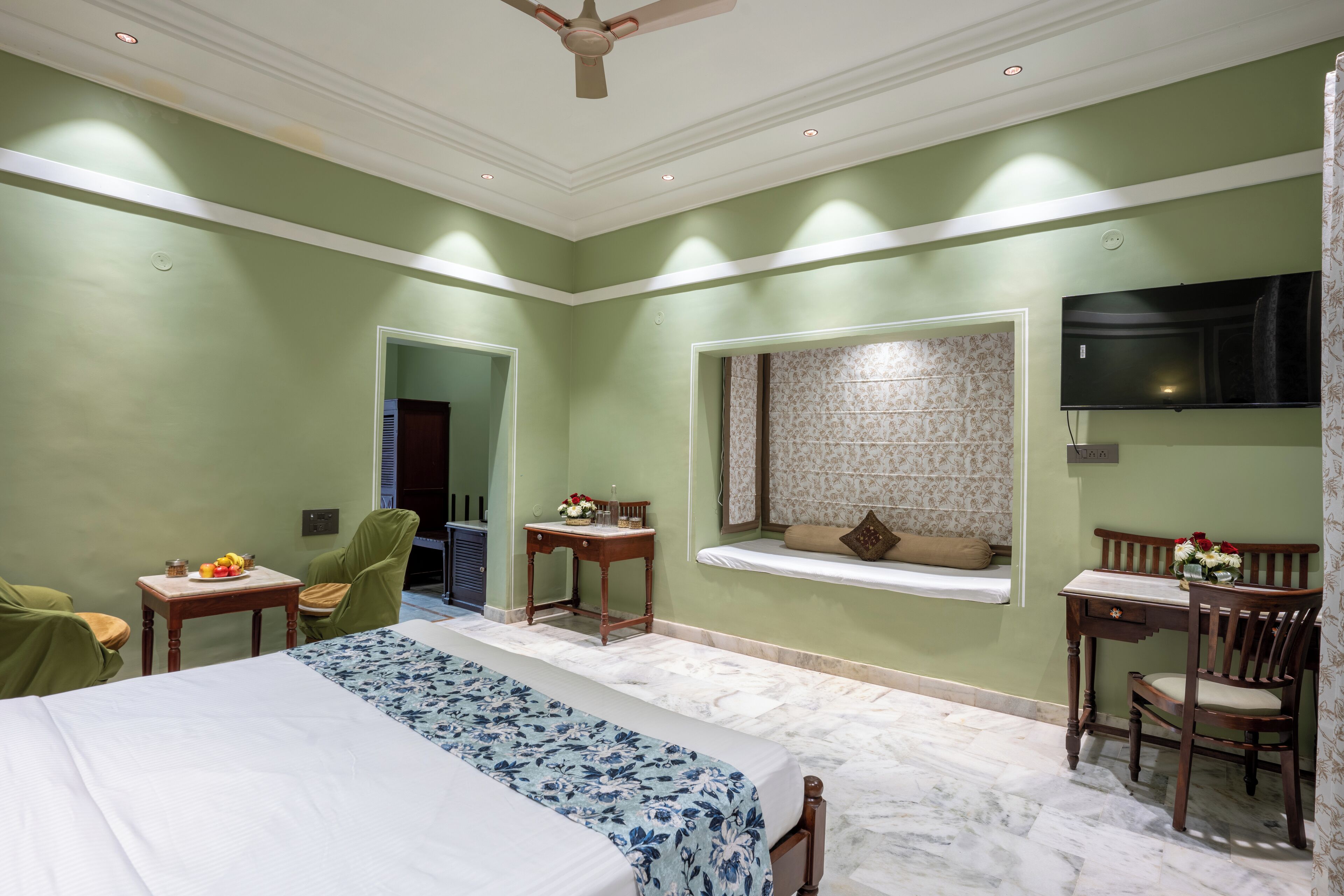 Habitación de hotel con cama, escritorio, silla, televisor y ventana con vistas.