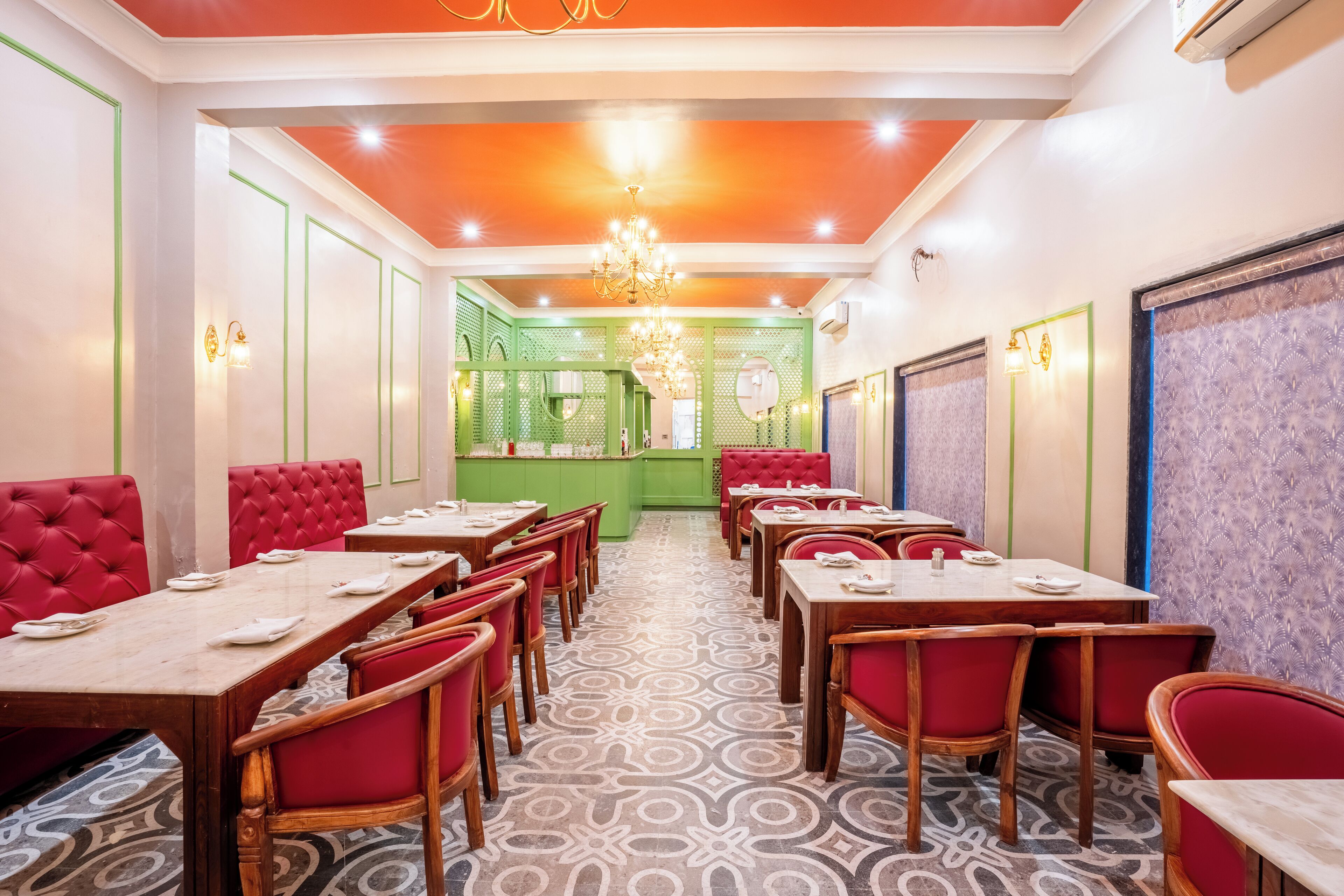 A restaurant with red upholstered booths, wooden tables, and patterned floor tiles.