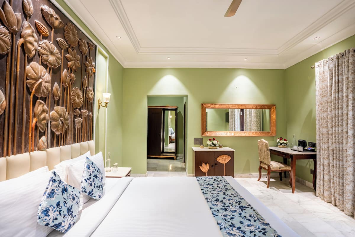 Una habitación de hotel con una cama grande, un escritorio, una silla y un espejo.