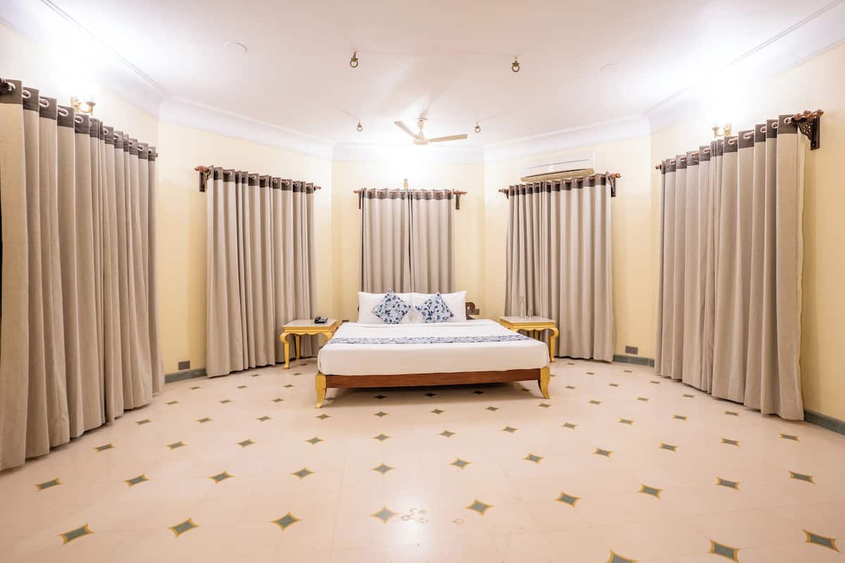 Un dormitorio amplio con una cama grande, dos mesitas de noche y un ventilador de techo.