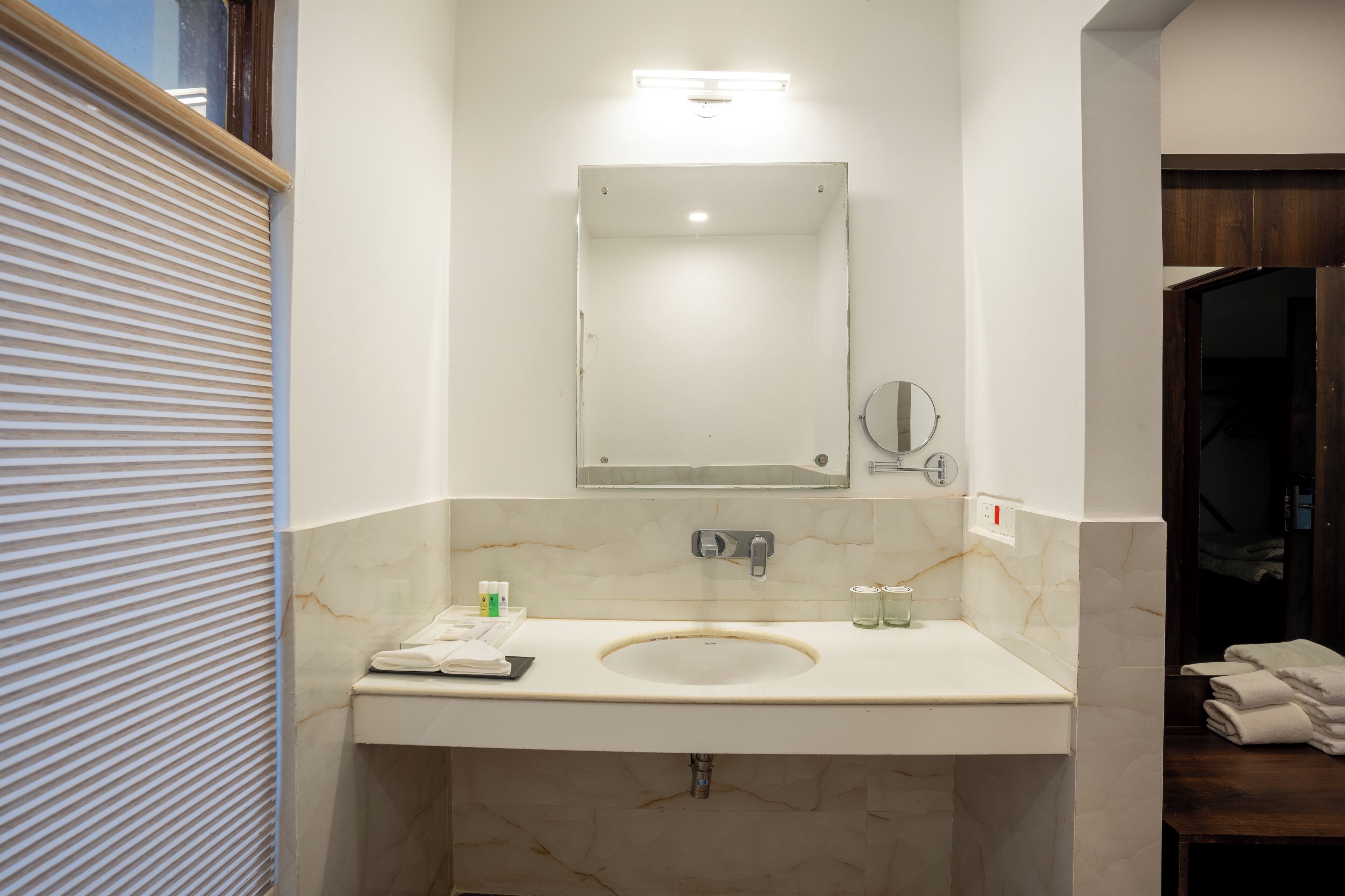 A bathroom with a marble sink, a mirror, and a towel rack.